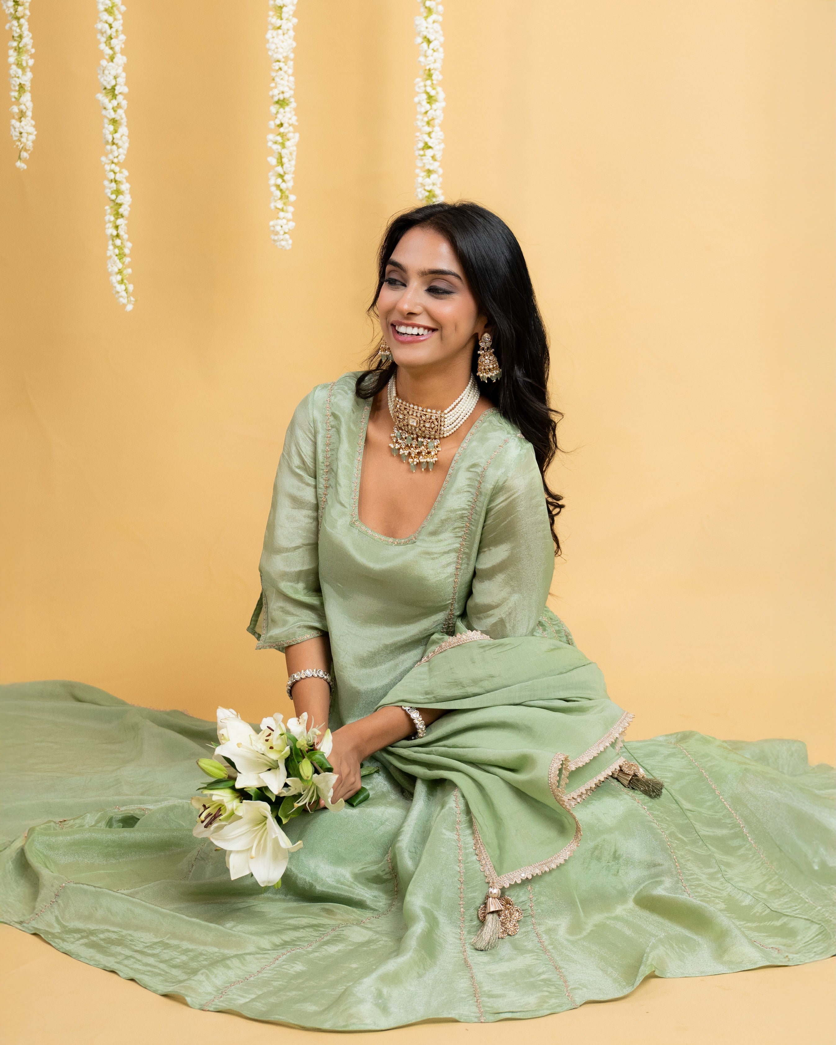 Pretty fashion clothing model in green Indian designer suit holding flower bouquet